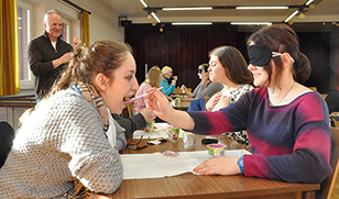 Eine Schülerin füttert eine andere, welche mit einem Tuch blind gemacht wurde.